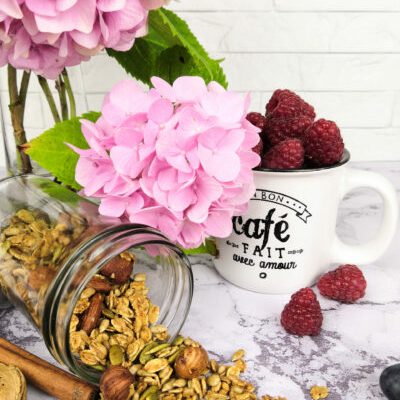 Granola de fruits secs caramélisé au miel avec une tasse de framboises et des hortensias roses